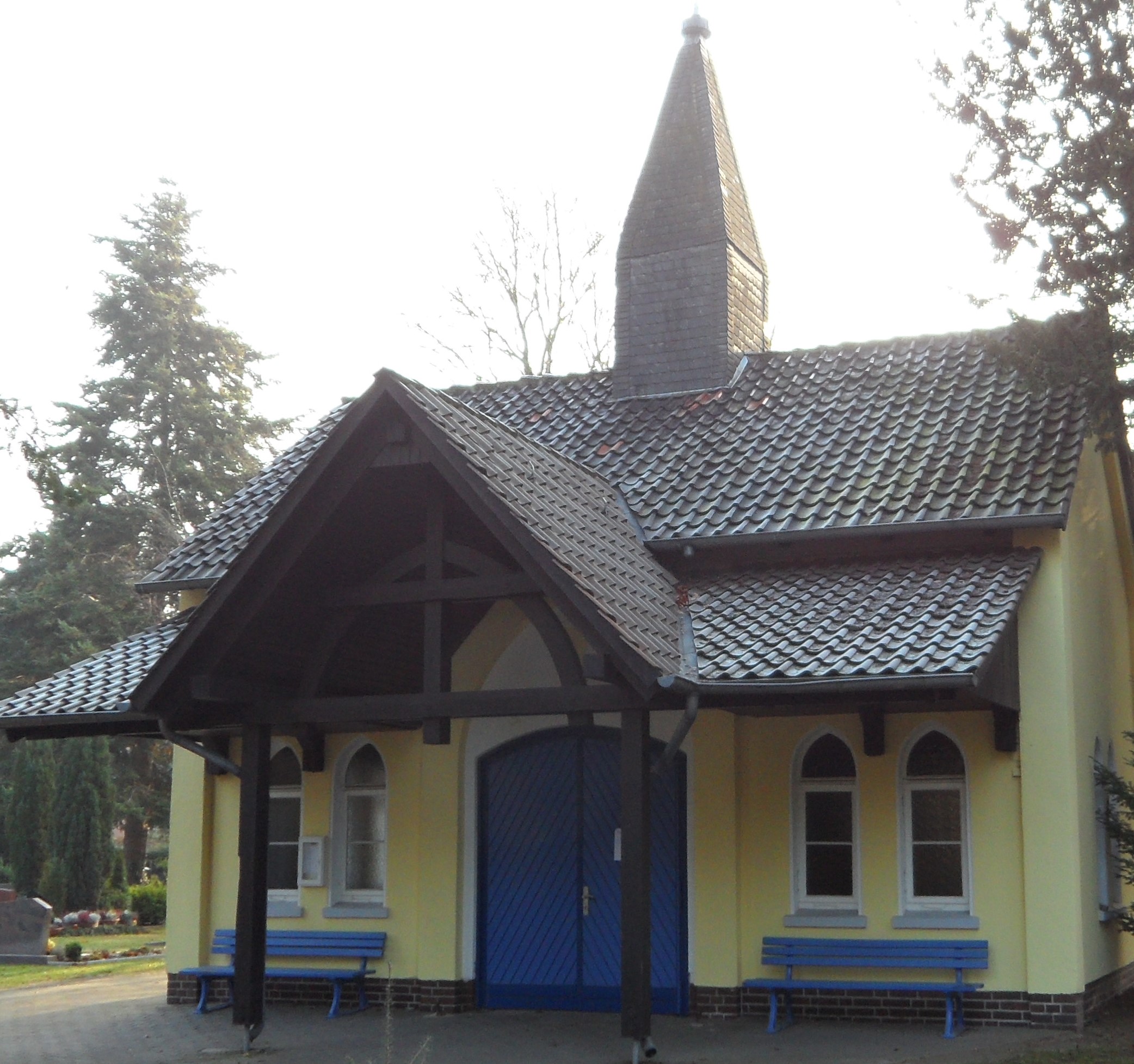 Friedhofskapelle mit spitzem Türmchen und blauer Eingangstür, im Hintergrund Bäume. ©Stadt Laatzen