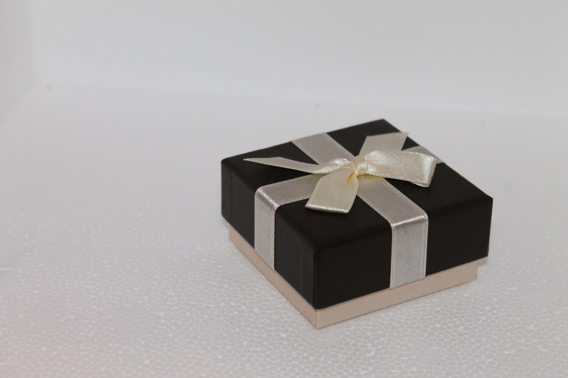 Weiße Schachtel mit schwarzem Deckel und weißer Schleife