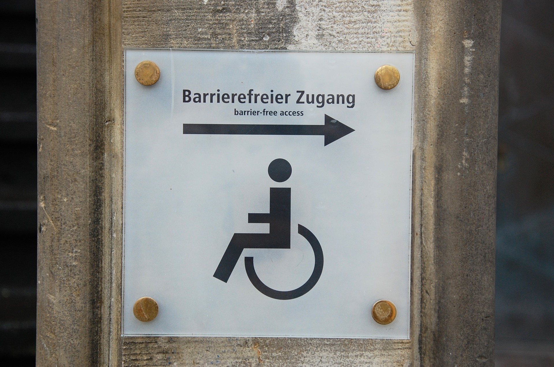 Ein Schild auf welchem Barrierefreier Zugang in Deutsch und Englisch geschrieben steht und ein Rollstuhlfahrer als Piktogramm abgebildet ist. ©Pixabay