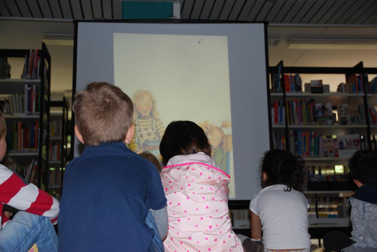 Kinder sitzen vor einer Leinwand