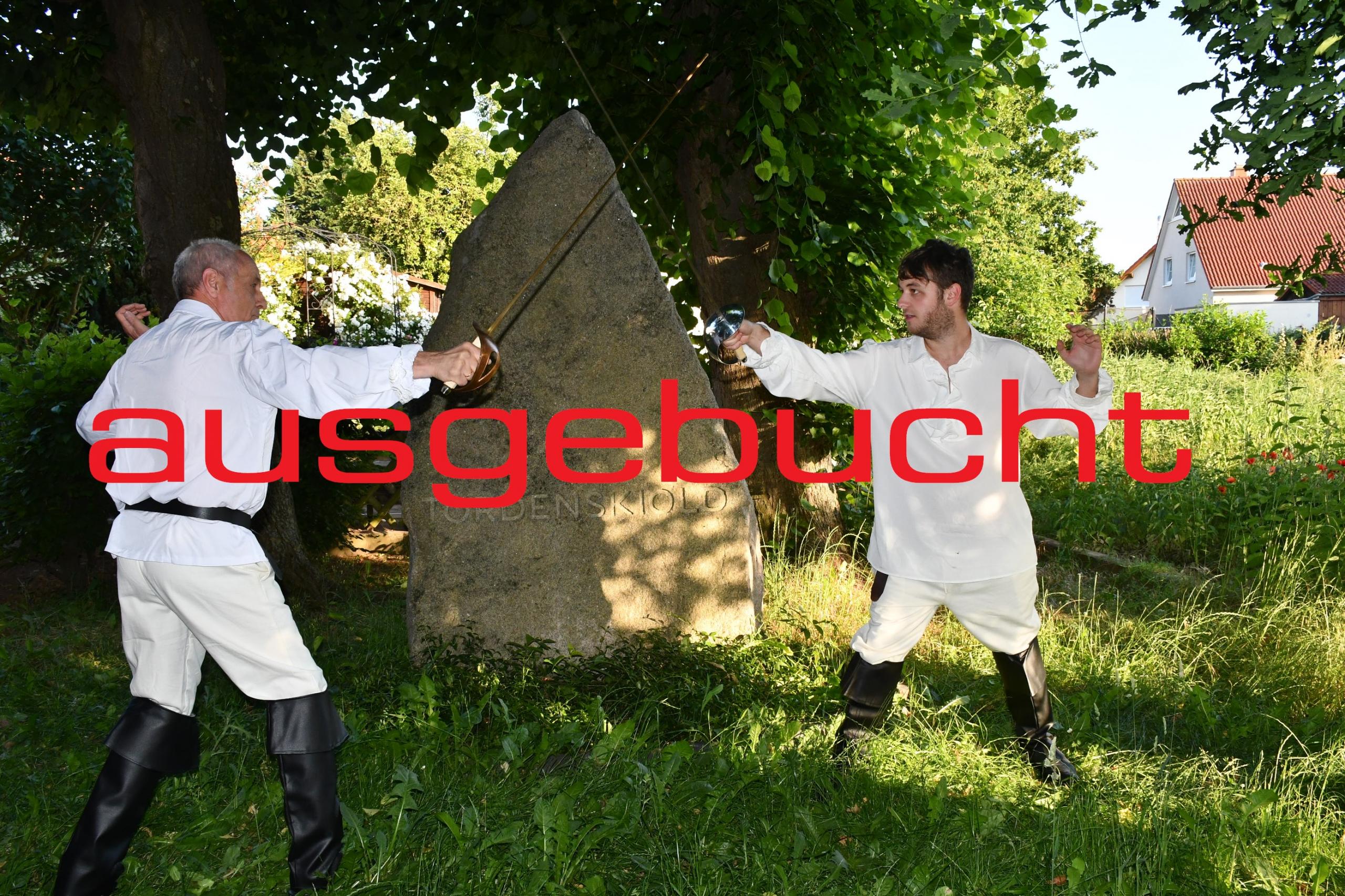 Nachgestelltes Duell mit Degen. Zwei Männer stehen sich bewaffnet gegenüber mit Schriftzug "abgesagt"