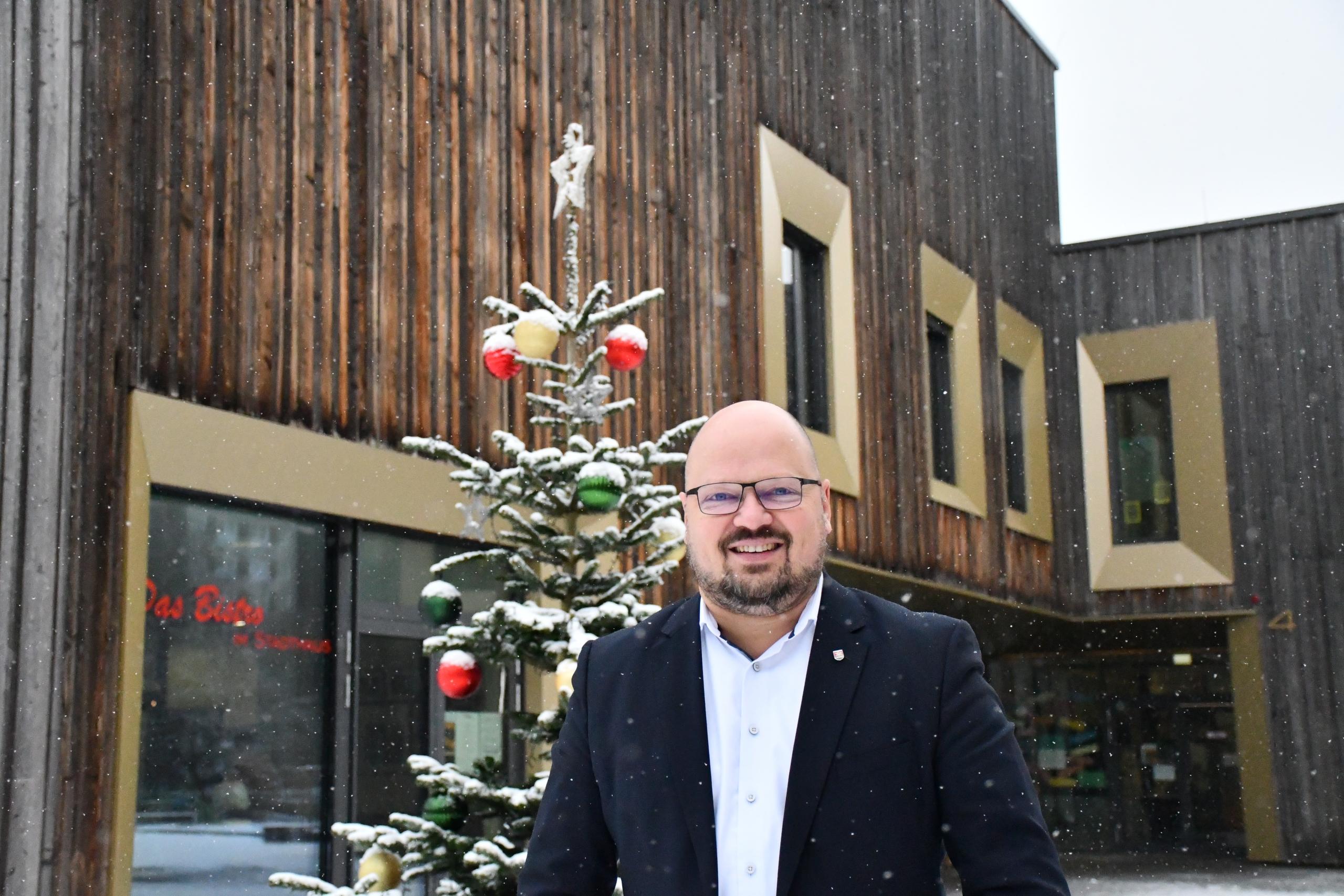 Portrait von Bürgermeister Kai Eggert, der vor dem Weihnachtsbaum am Stadthaus steht