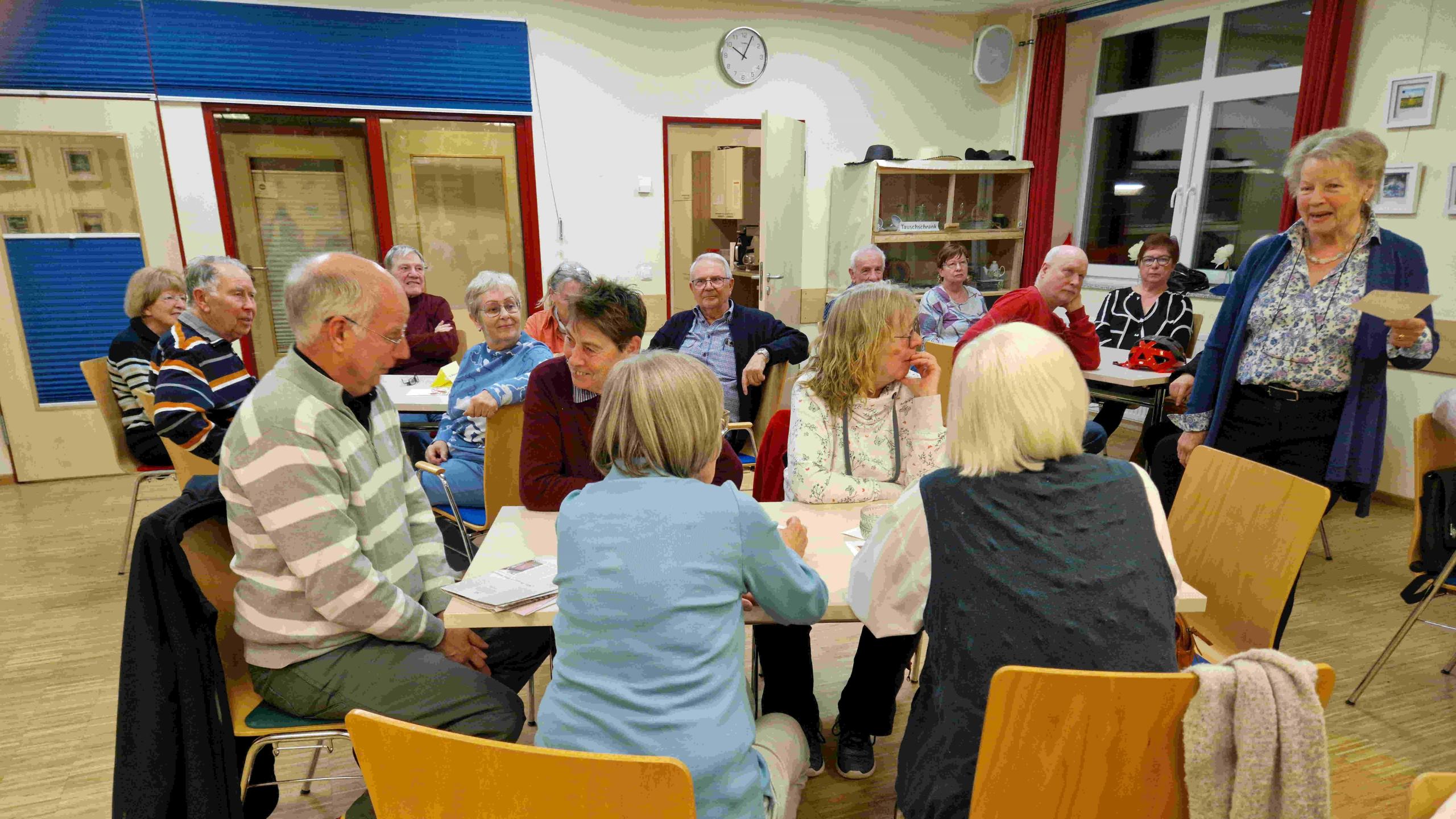 Personengruppe an Tischen, die miteinander sprechen