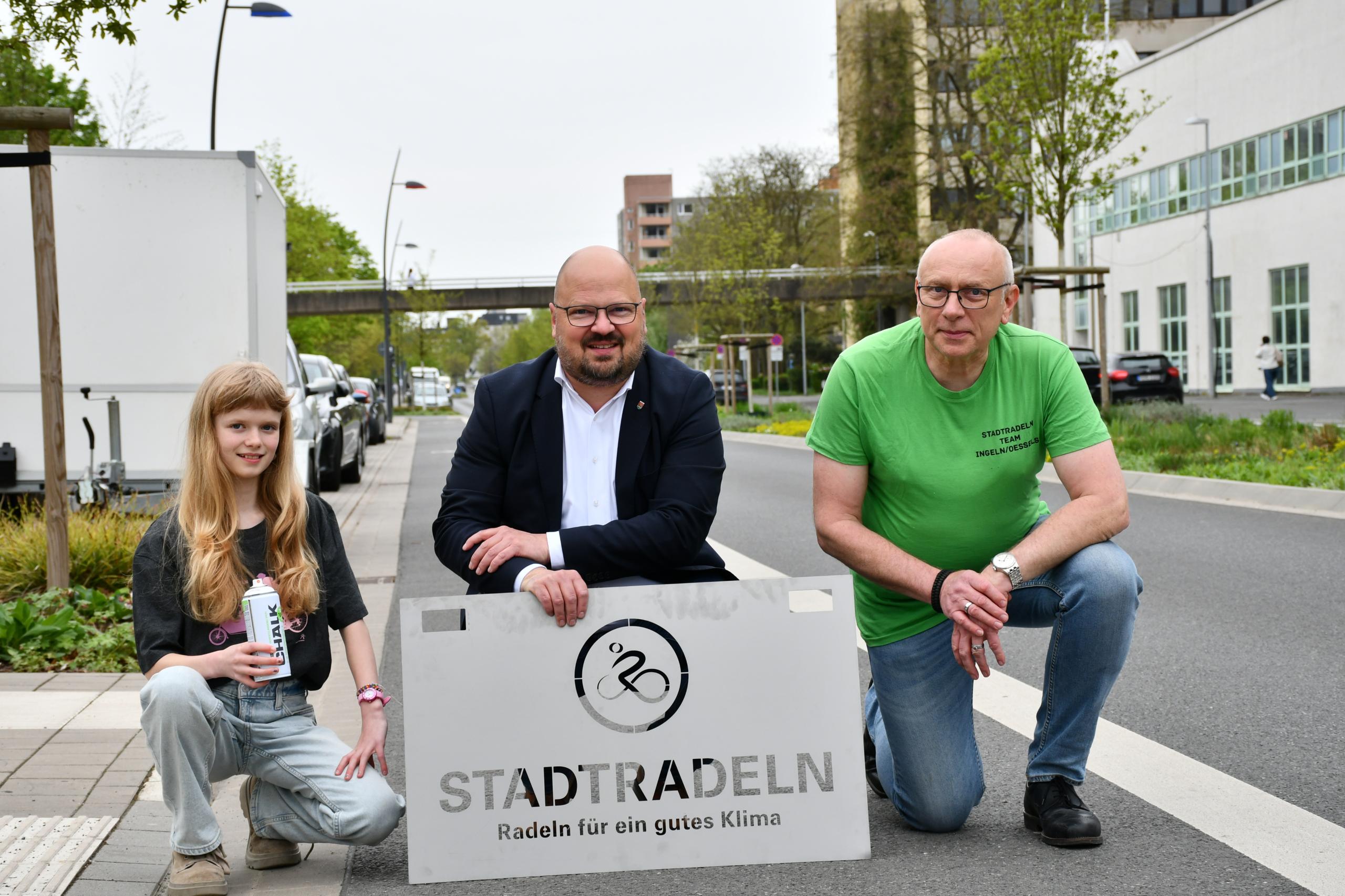 Werbebild mit zwei Männern und einem Mädchen und einem STADTRADEL Schild.
