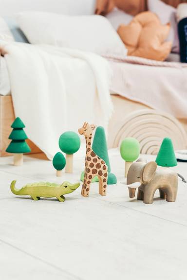 Holz-Spielzeugfiguren, Krokodil, Giraffe, Elefant und mehrere Bäume stehen auf dem Fußboden