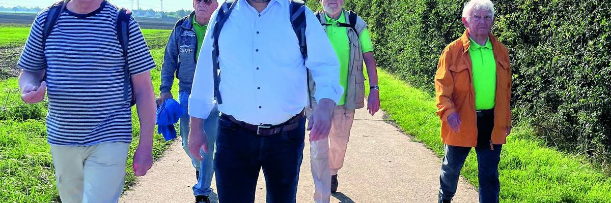 Bürgermeister Kai Eggert geht mit vier weiteren Männern auf einem Feldweg entlang.