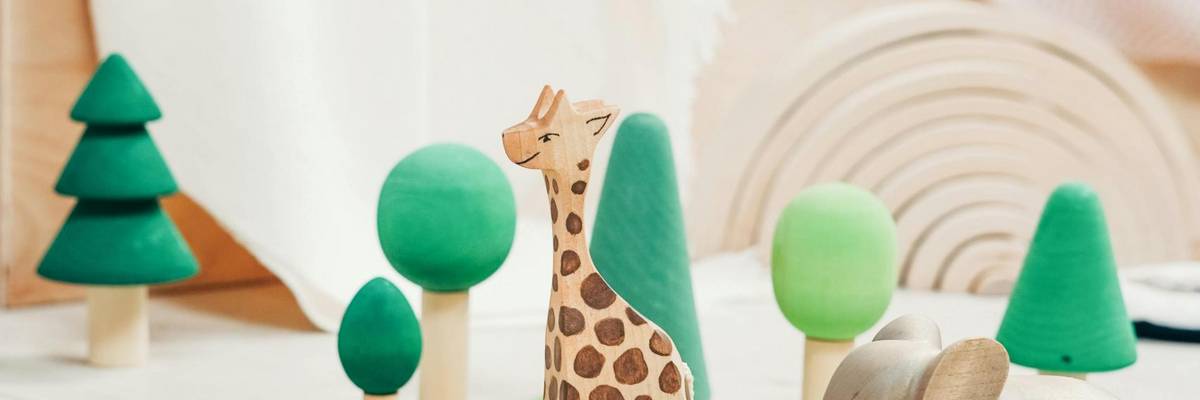 Holz-Spielzeugfiguren, Krokodil, Giraffe, Elefant und mehrere Bäume stehen auf dem Fußboden