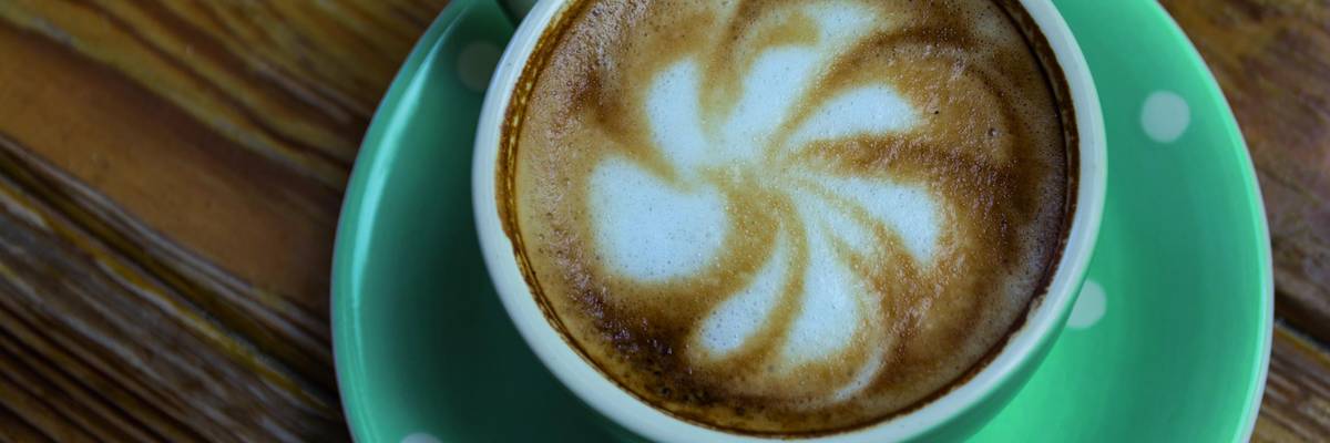 Kaffee in einer gepunkteten Tasse mit dekorativem Schaum