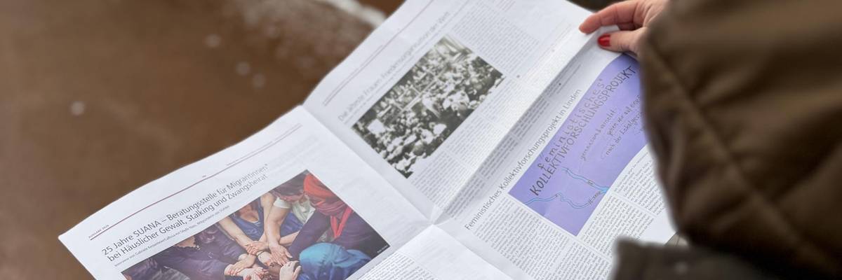 Eine Frau betrachtet eine Zeitschrift. Im Hintergrund Asphalt und etwas Schnee.