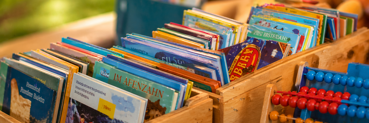 verschiedene Bücherkisten, ein Abakus lehnt davor