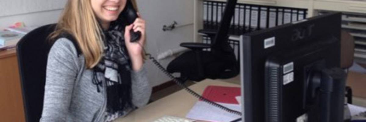 Junge Frau am Schreibtisch sitzend mit Telefon in der Hand