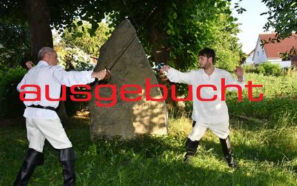 Nachgestelltes Duell mit Degen. Zwei Männer stehen sich bewaffnet gegenüber mit Schriftzug "abgesagt"