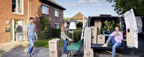 Mehrere Personen tragen Umzugskartons und beladen ein Fahrzeug.