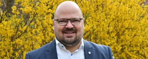Portraitfoto von Bürgermeister Kai Eggert vor blühenden Forsythien