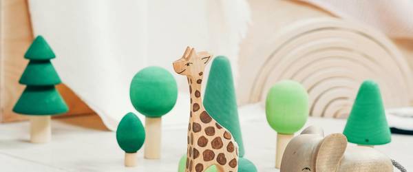 Holz-Spielzeugfiguren, Krokodil, Giraffe, Elefant und mehrere Bäume stehen auf dem Fußboden