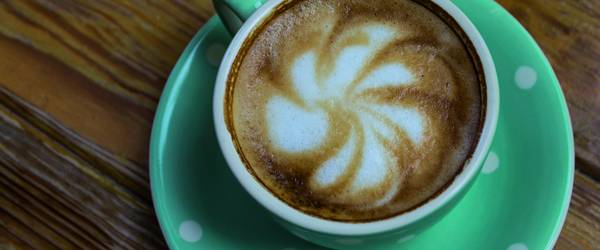 Kaffee in einer gepunkteten Tasse mit dekorativem Schaum