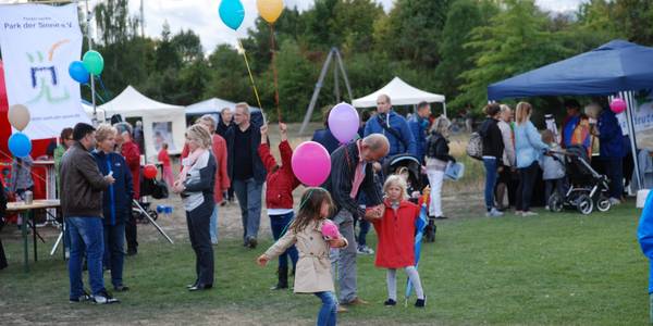 Menschengruppe mit tanzenden Kindern und Ballons im Vordergrund