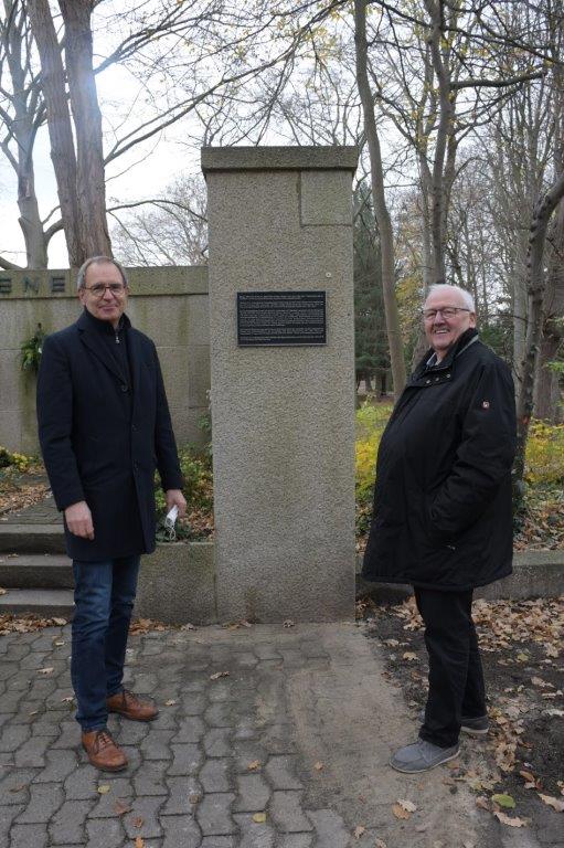 Bürgermeister Köhne und Ortsbürgermeister Stuckenberg stehen vor der Erklärtafel am alten Ehrenmal