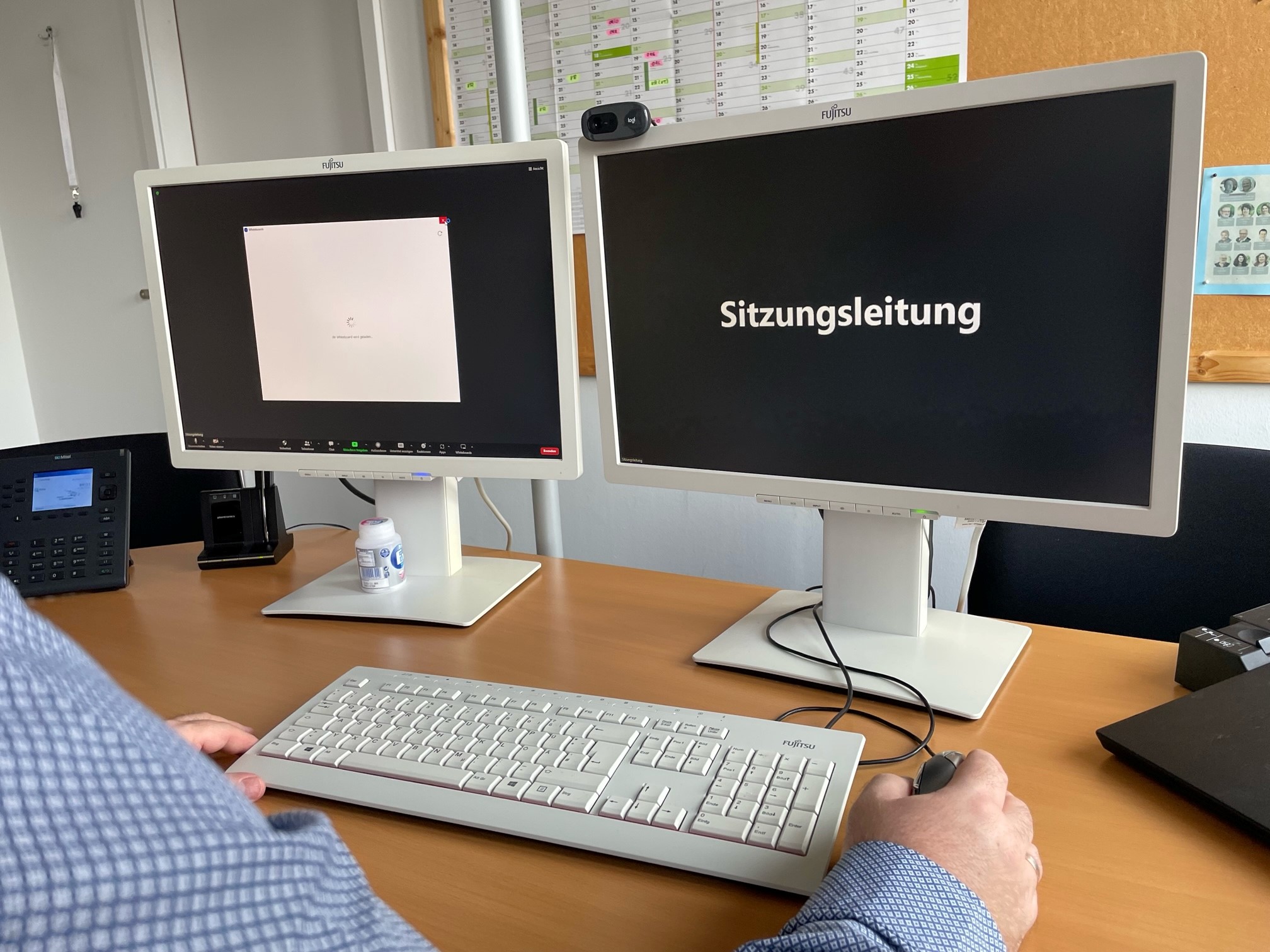 Symbolbild Hybridsitzung ©Stadt Laatzen/Ilka Hanenkamp-Ley Eine Person sitzt vor zwei Bildschirmen. Auf einem Bildschirm steht Sitzungsleitung, auf dem anderen ist ein weißes Kästchen zu sehen.