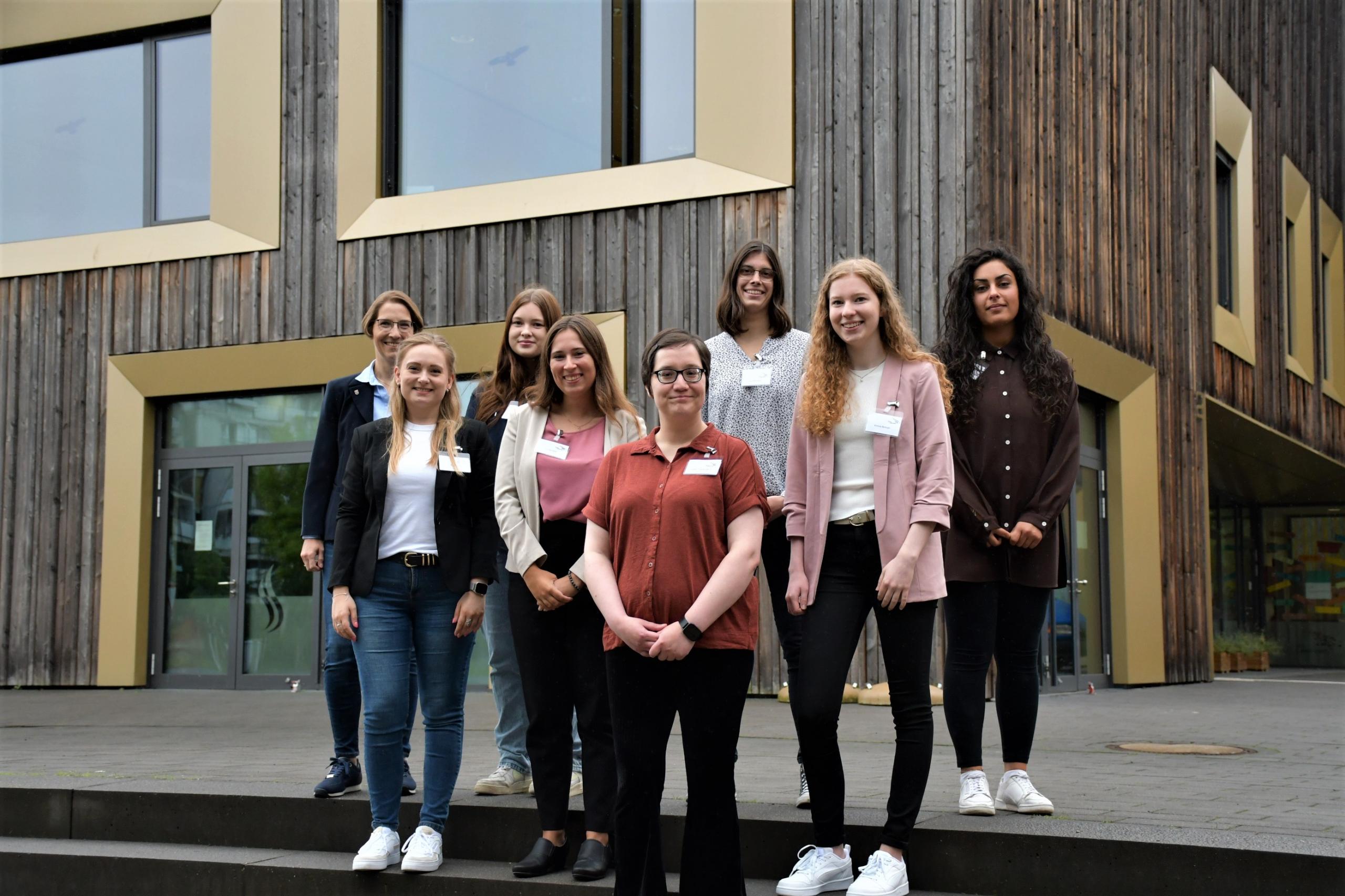 Eine Gruppe von Menschen steckt vor dem Stadthaus und lächelt in die Kamera.