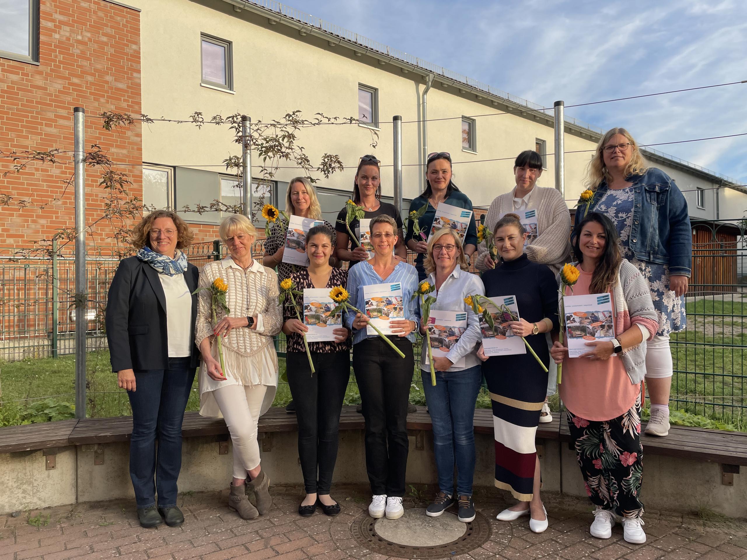 Haben ihre Aufbauqualifizierung in der Kindertagespflege erfolgreich absolviert: Doreen Rätzel, Marlen Rätzel, Julia Stepanov und Sandy Köster mit Dozentin Uschi Drude von der Werk-statt-Schule e.V. (oben v.l.) und Leiterin der städtischen Kinderbetreuung Babett Fandrich sowie Dozentin Michaela Linkhof von der Werk-statt-Schule mit Seray Ucucu, Melani Voigt, Katrin Friederike Benke, Dilara Mohammadi, Stefanie Kubitzke (unten v.l.). ©Stadt Laatzen Eine Gruppe Frauen lächelt in die Kamera. Einige von ihnen halten Sonnenblumen und Zertifikate vor sich.