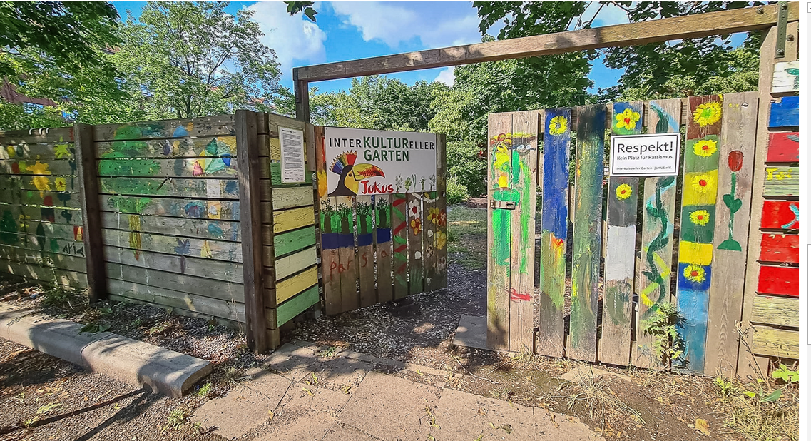 Mit Blumen und Rosen bunt bemalter Eingangszaun des interkulturellen Gartens