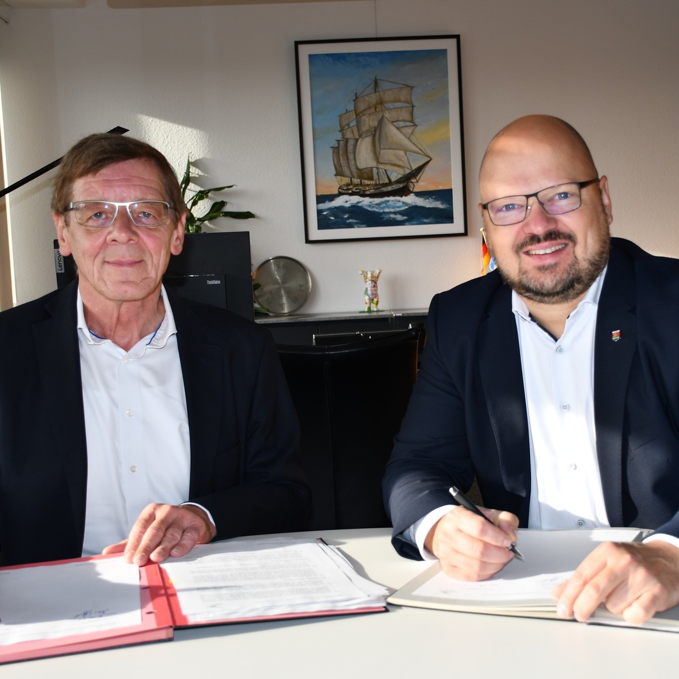 Zwei Männer schauen in die Kamera, nachdem sie einen Vertrag unterzeichnet haben.