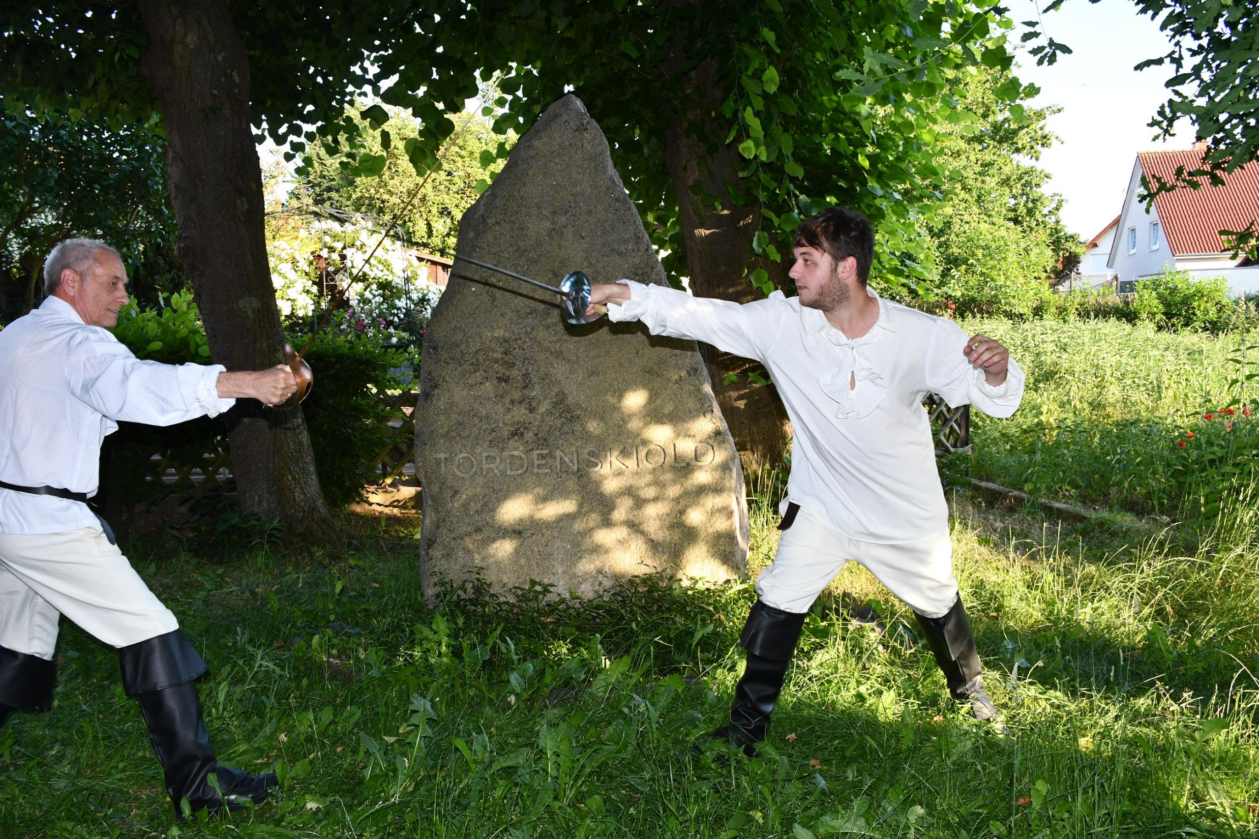 Zwei Männer in altertümlichen Gewändern duellieren sich vor dem Tordenskiold-Gedenkstein.