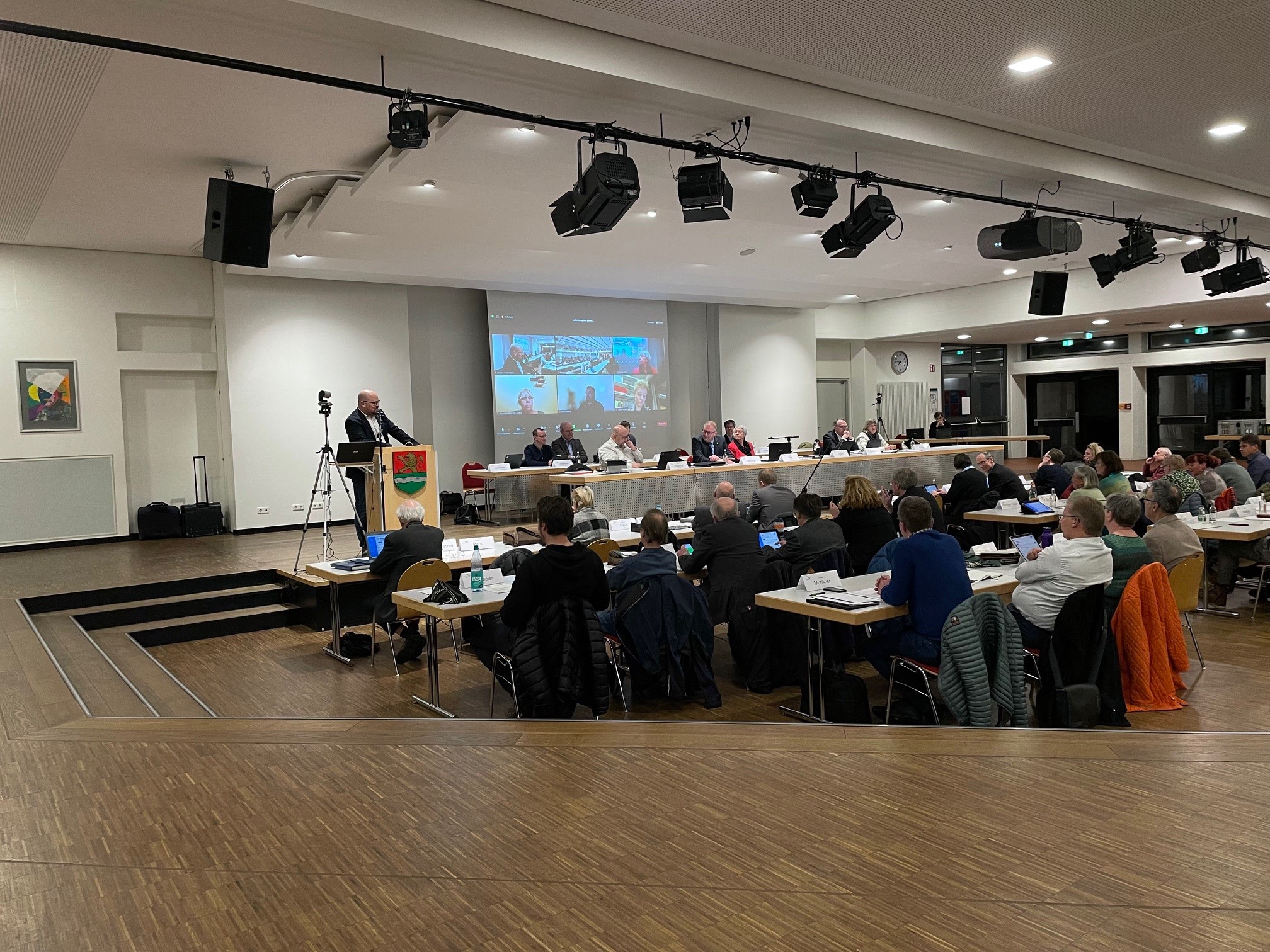 Eine sitzende Menschenmenge blickt zum Podium, an dem eine Rede gehalten wird.