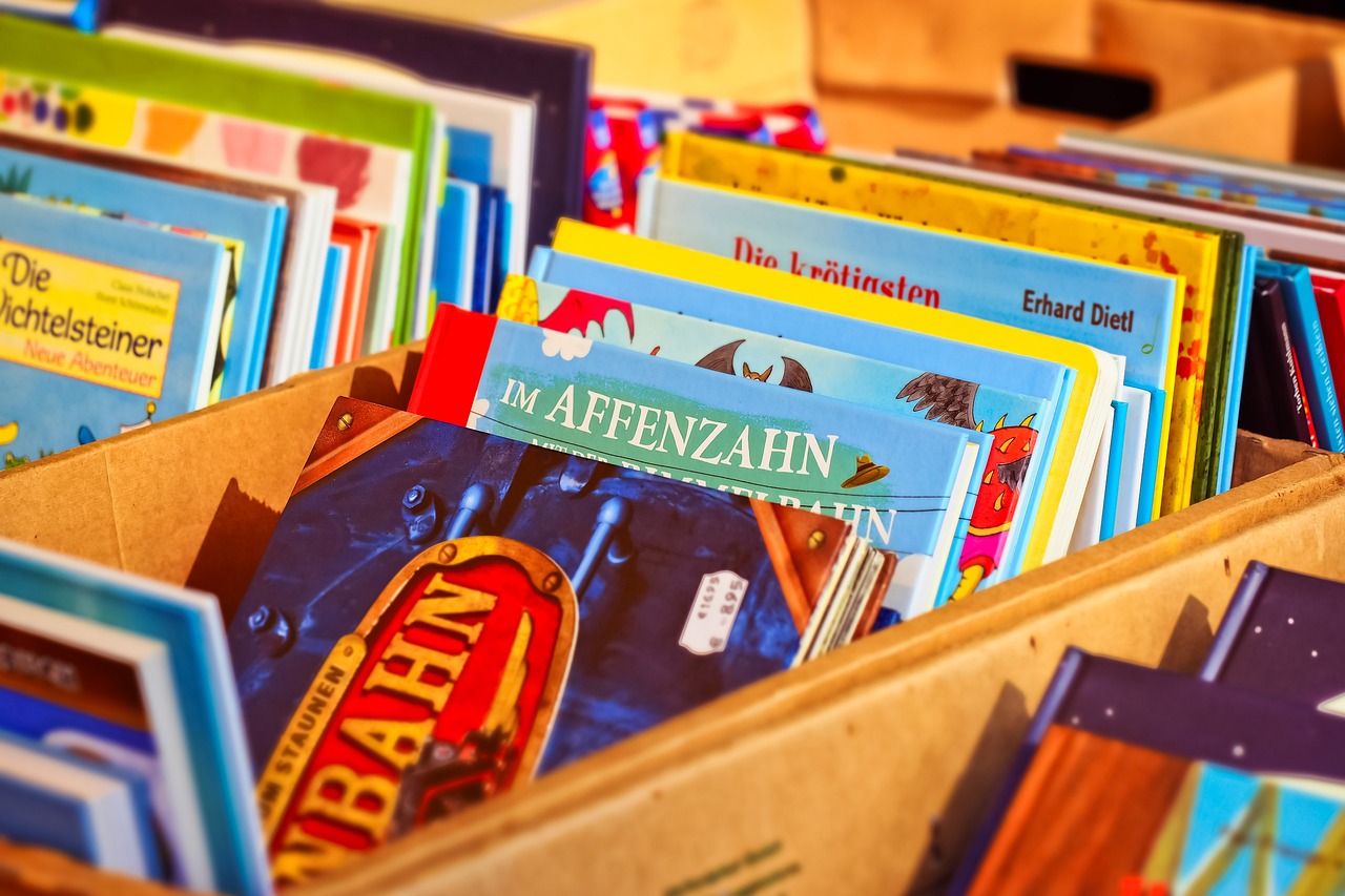Kinderbücher lehnen in einem Holzkasten aneinander.