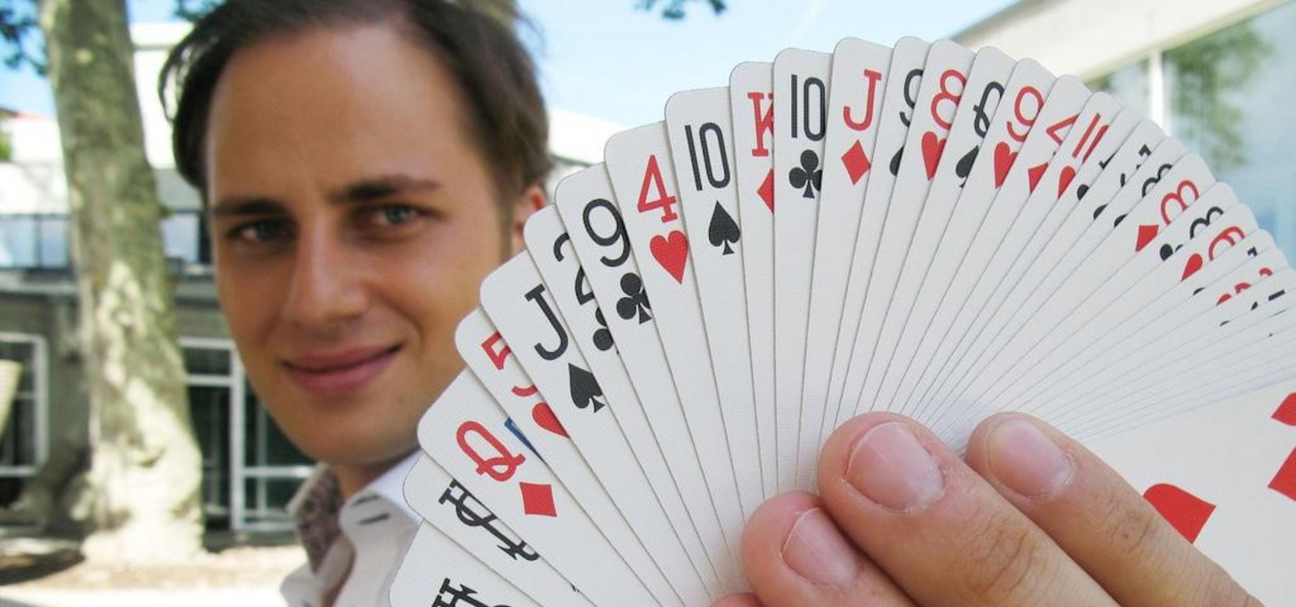 Mann hält Kartendeck vor seinem Gesicht