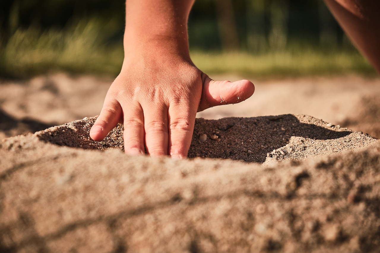 Eine Kinderhand spielt mit Sand