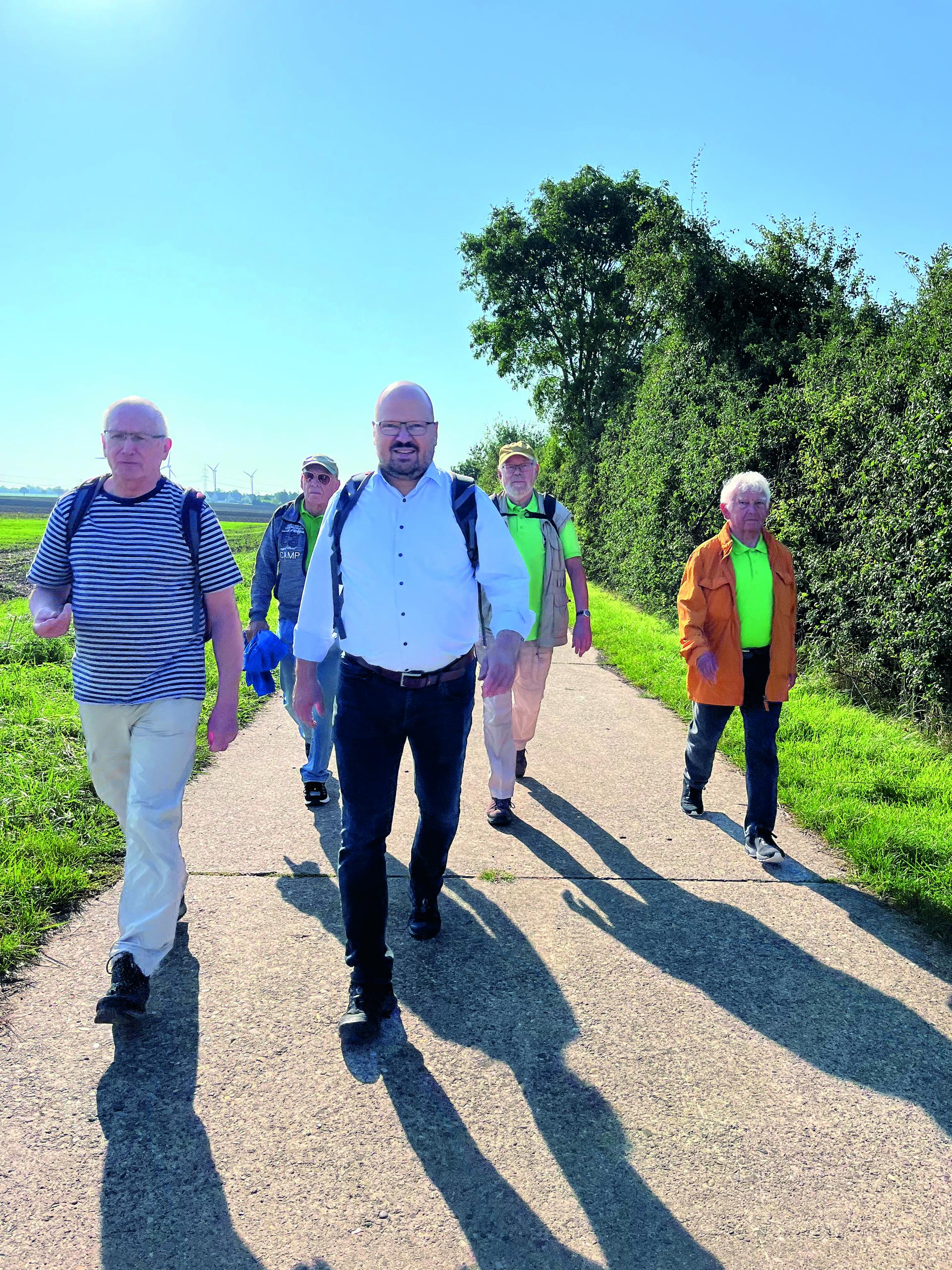 Bürgermeister Kai Eggert geht mit vier weiteren Männern auf einem Feldweg entlang.