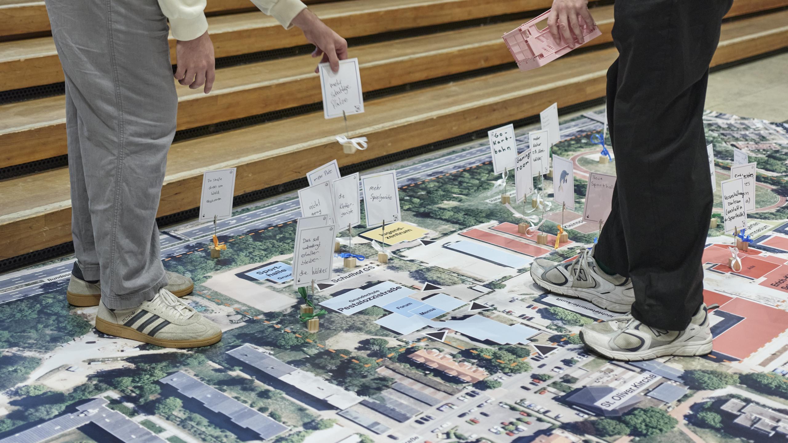 Auf einer großen Planvorlage bewegen Hände verschiedene Aufsteller