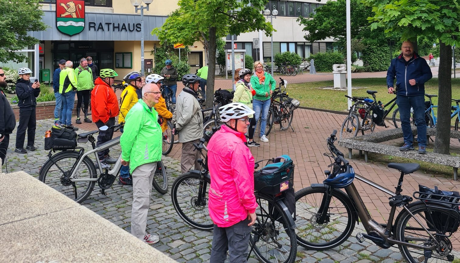 Eine Gruppe Radfahrer versammelt sich vor dem Rathaus.