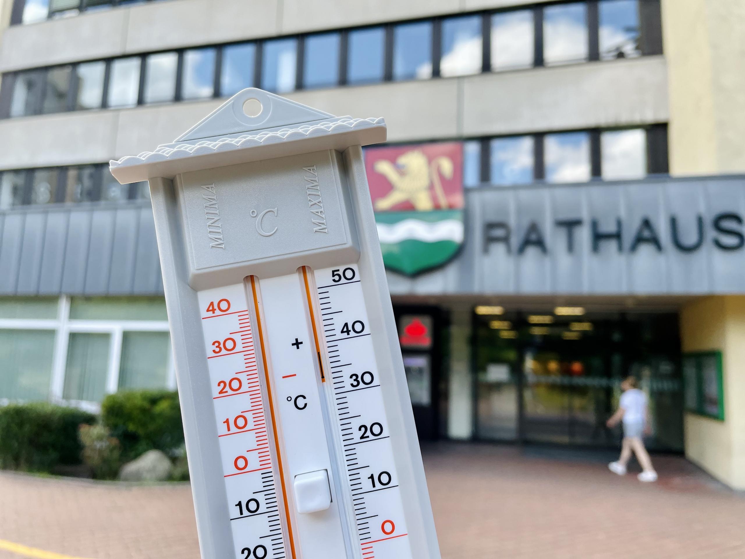 Der Deutsche Wetterdienst hat eine amtliche Hitzewarnung für die Region Hannover veröffentlicht ©Stadt Laatzen Eine Hand hält ein analogen Thermometer; im Hintergrund sieht man das Rathaus