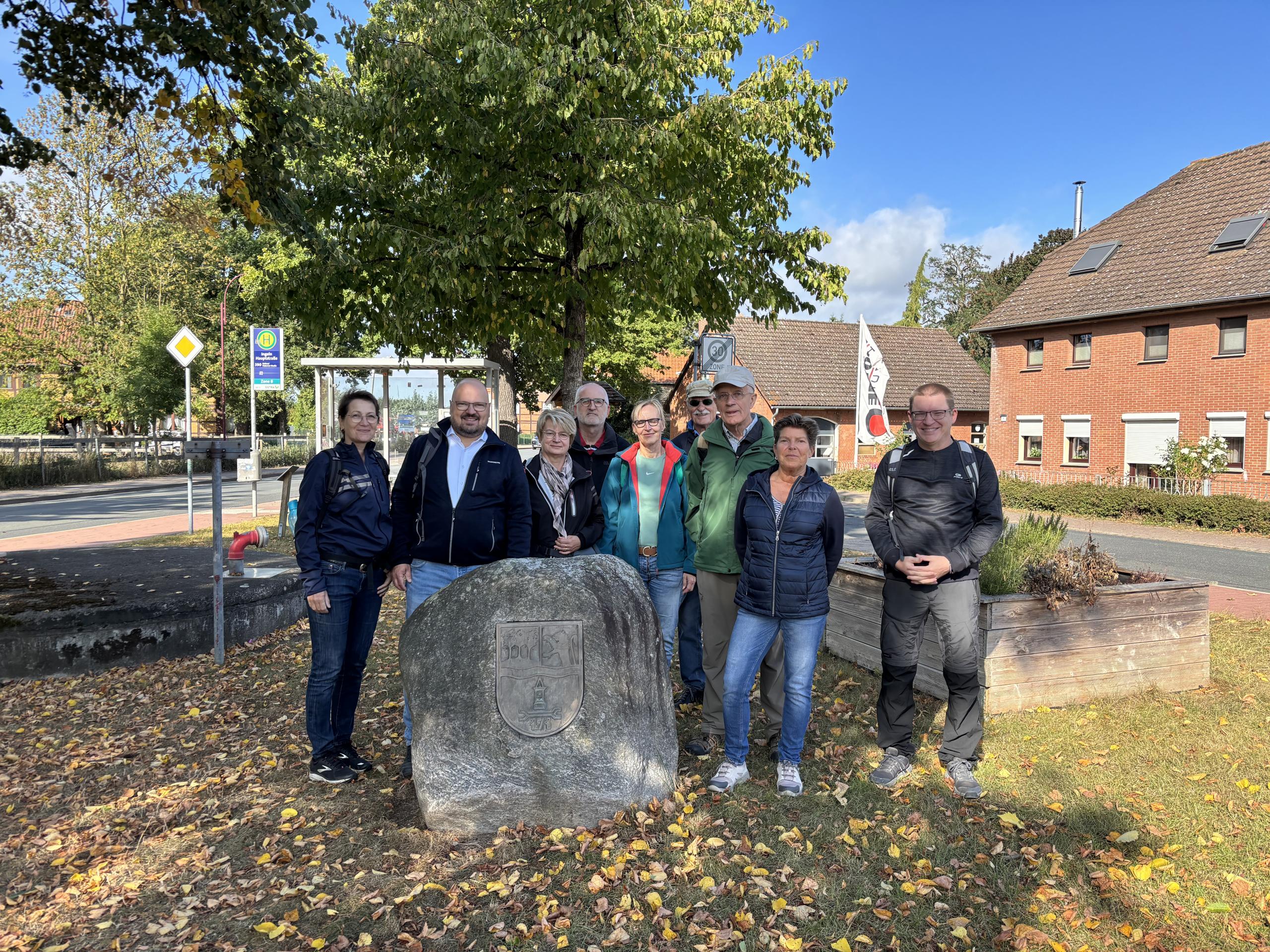 Eine Gruppe von Menschen stehen gemeinsam mit Bürgermeister Kai Eggert in Ingeln-Oessels vor einem großen Stein mit Gravur.