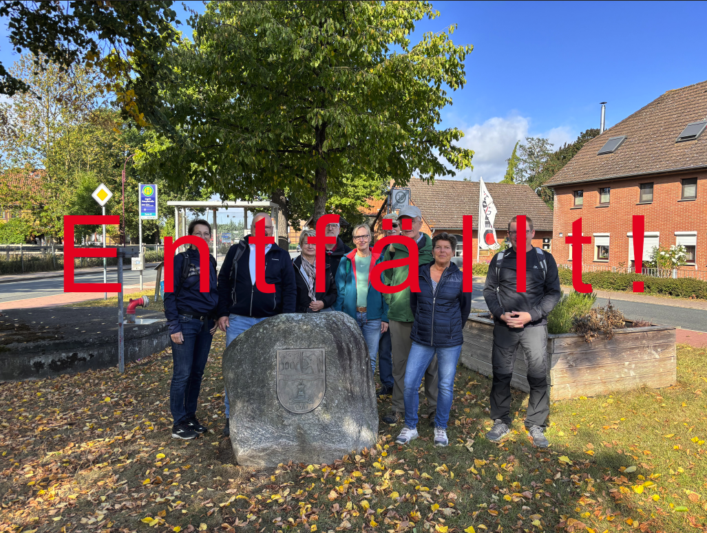 Eine Gruppe von Menschen stehen gemeinsam mit Bürgermeister Kai Eggert in Ingeln-Oessels vor einem großen Stein mit Gravur. Darüber der Schriftzug entfällt.