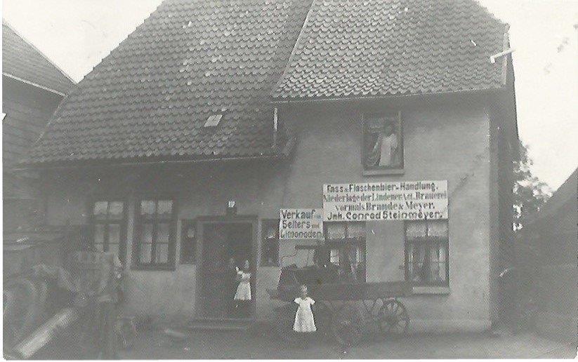 Schwarz-Weiß-Foto eines Hauses mit Menschen und Kutsche vor dem Haus