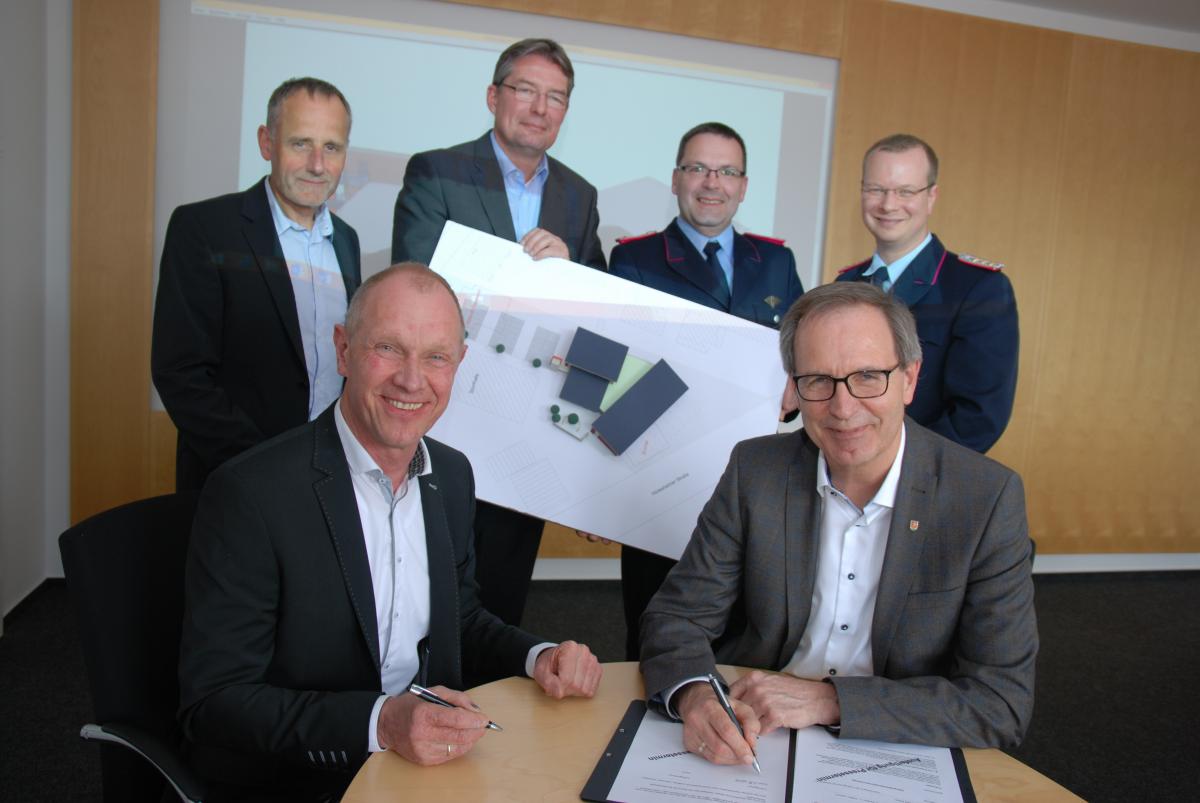 Detlef Meyer, Geschäftsführer der Reinhold Burghardt Bauunternehmung GmbH, und Bür-germeister Jürgen Köhne unterschreiben den Generealunternehmer-Vertrag für den Neubau der Feuerwache Süd. Dahinter vlnr: Prokurist Andreas Heinecke, Architekt Stefan Franke, Rethens Ortsbrandmeister Dennis Schröder und Stadtbrandmeister Sebastian Osterwald. Eine Gruppe unterschreibt einen Vertrag