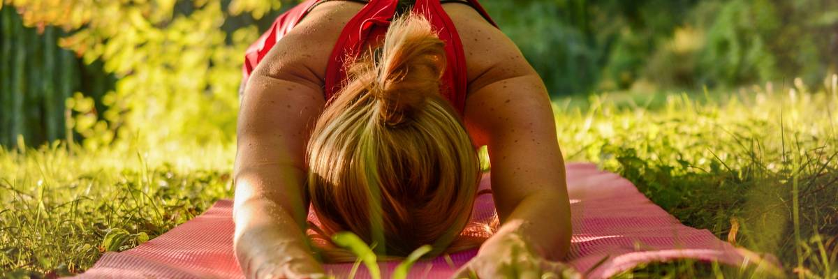Frau macht Yogafigur auf einer grünen Wiese im Park