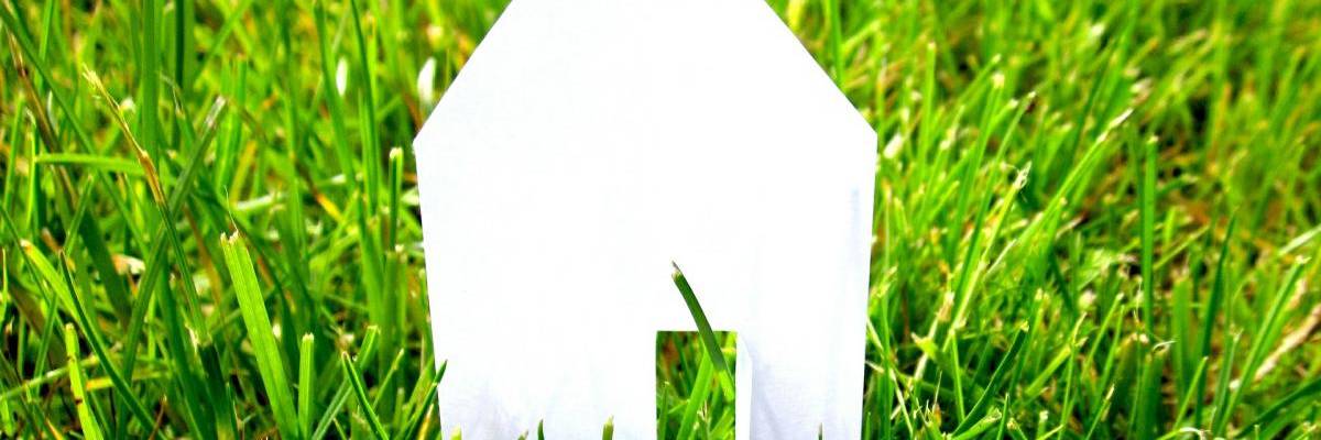 Häusersilhouette aus Papier auf grünem Rasen