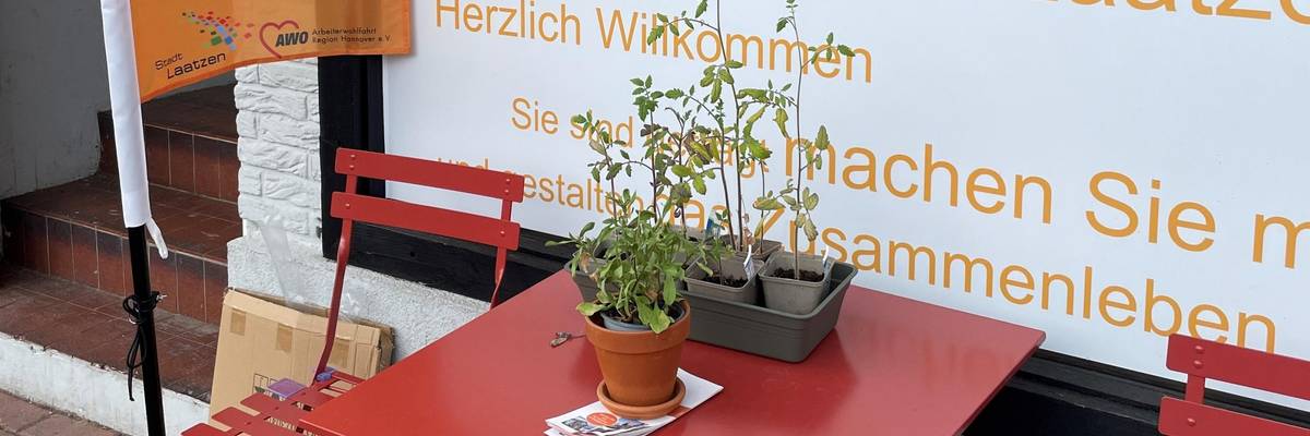 Schaufenster des Stadtteilladens. Davor stehen ein roter Tisch und rote Stühle.