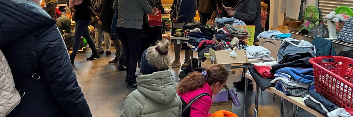 Eine Gruppe Frauen und Kinder, die an verschiedenen Flohmarktständen stehen.