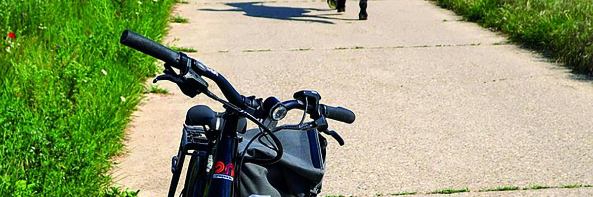 Ein Fahrrad steht auf dem Feldweg. Im Hintergrund ist eine Reiterin zu sehen.