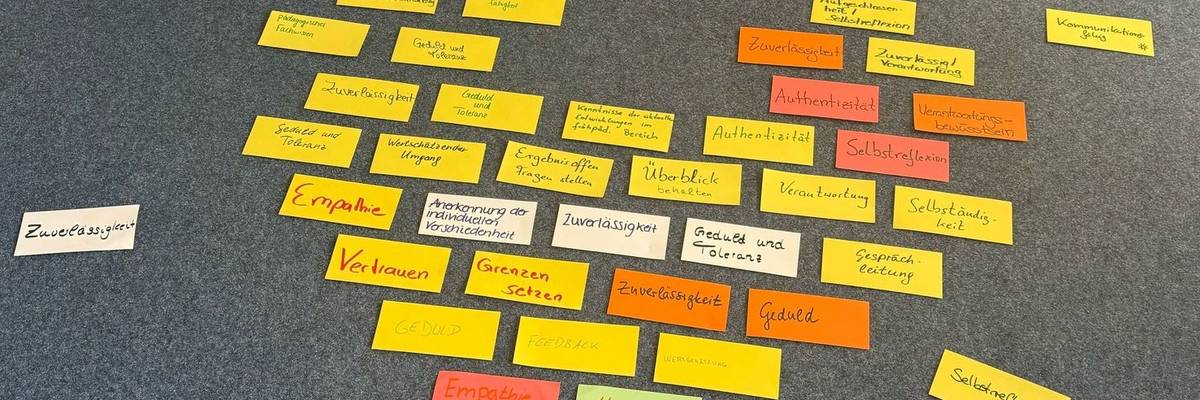 Auf dem Fußboden liegen Metaplankarten in Herzform. Auf den Metaplankarten stehen Begriffe.
