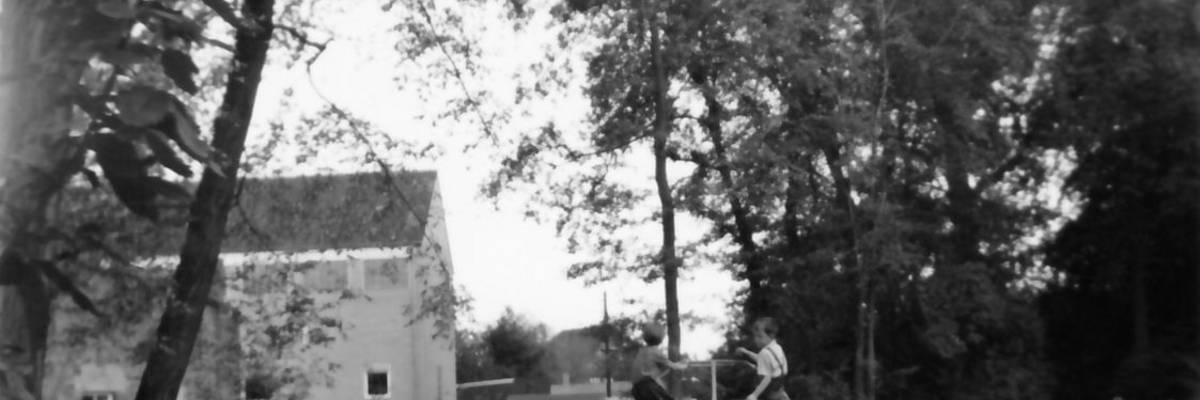 Spielplatz mit Kindern, im Hintergrund Häuser und Bäume