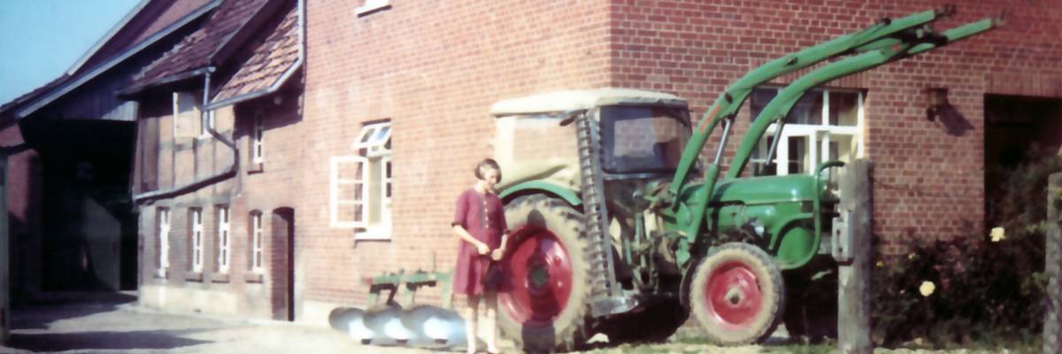 Dame im roten Kleid und Traktor vor einem einem Gebäude