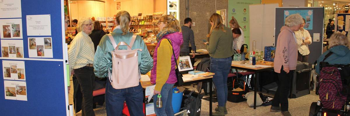 Zwei Messestände von städtischen Kindertagesstätten mit Mitarbeitenden und interessierten Personen, die im Gespräch sind