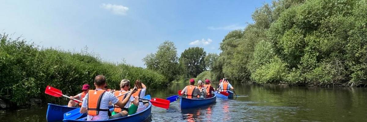 Kanuboote mit Personen besetzt, die auf einem Fluss fahren